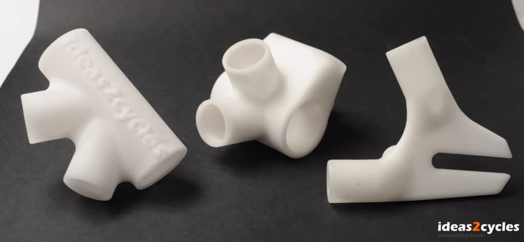 White plastic parts with central cylindrical shape and protruding arms against a black background.