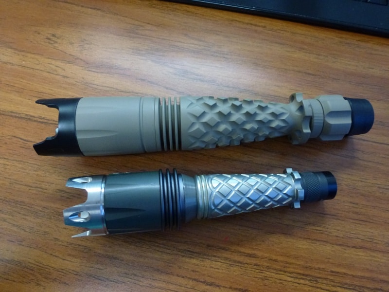 Two cylindrical metal or plastic objects with textured surfaces and pointed tips on a wooden surface.