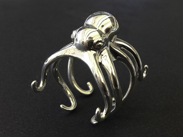 A silver-colored octopus figurine with eight curved tentacles on a black background.