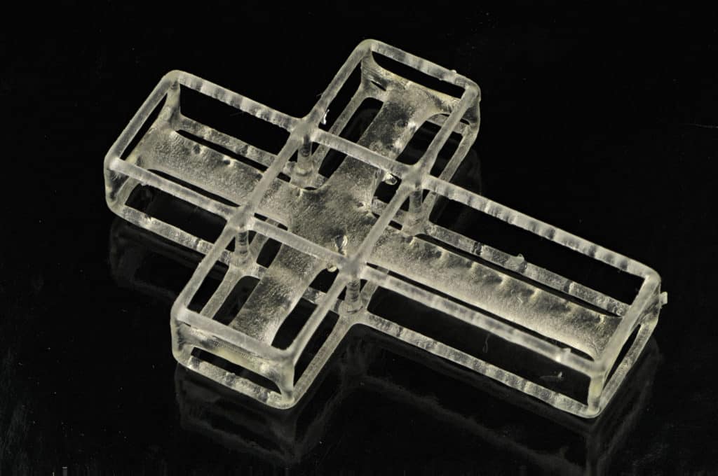 Transparent glass/acrylic cross suspended in air with visible intricate details.
