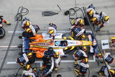 Pit stop scene with multiple people surrounding a vehicle.