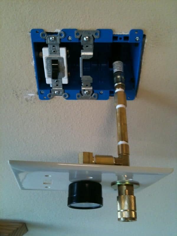Wall-mounted electrical box and air hose installation on beige background.