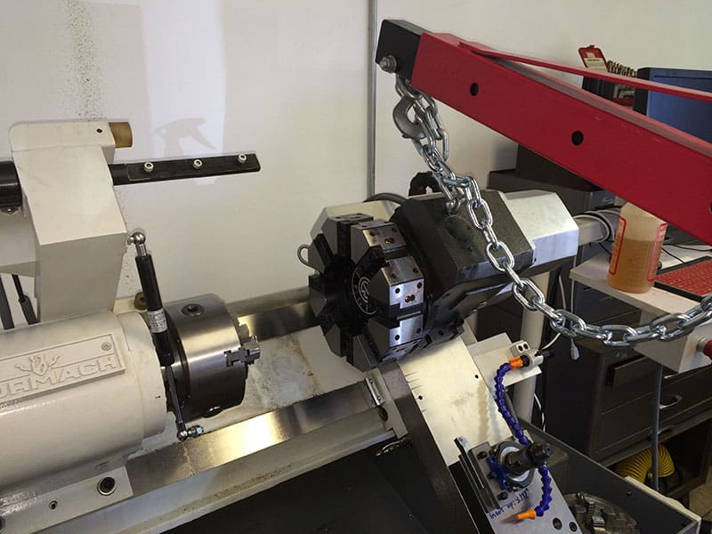 Lathe in industrial workshop with attached chain and various tools.