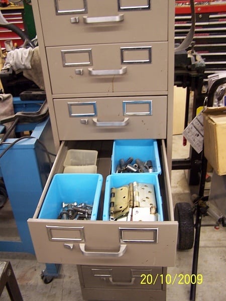 Tall beige metal filing cabinet with silver handles in a workshop.