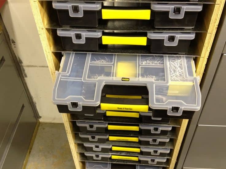 Clear plastic toolboxes with yellow handles stacked on metal shelves.