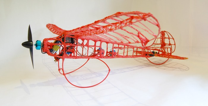 A red 3D-printed plane with propellers created using a 3Doodler pen.