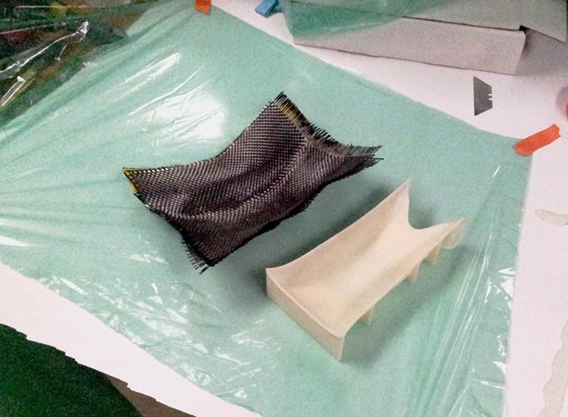 Carbon fiber molds on a green plastic sheet, showcasing their intricate details and textures.