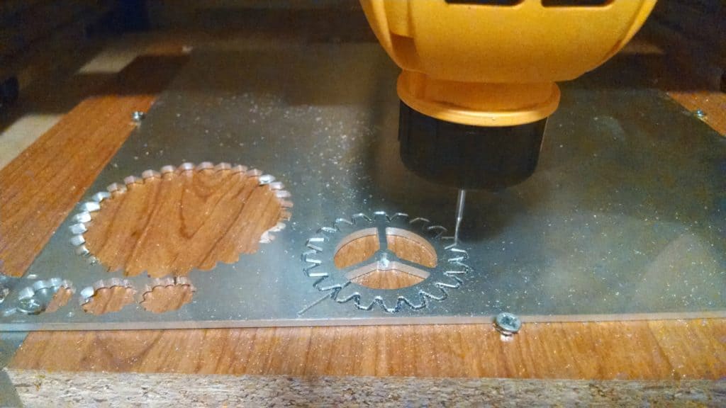 Yellow power tool cutting metal plate with intricate gears.