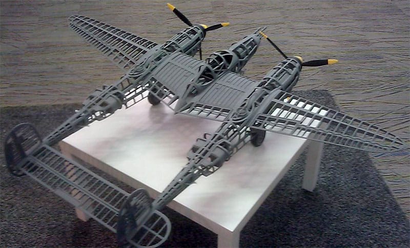 A P-38 Lightning aircraft model made from wire mesh on a table.