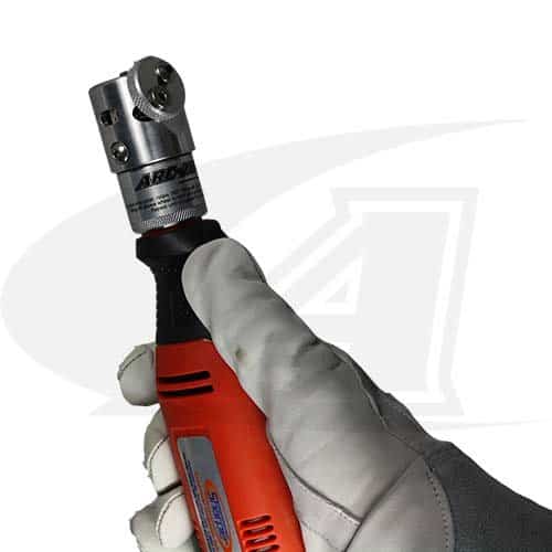 A hand in a white glove holding a Trode Grinder, an orange and silver tool with a round metal head.