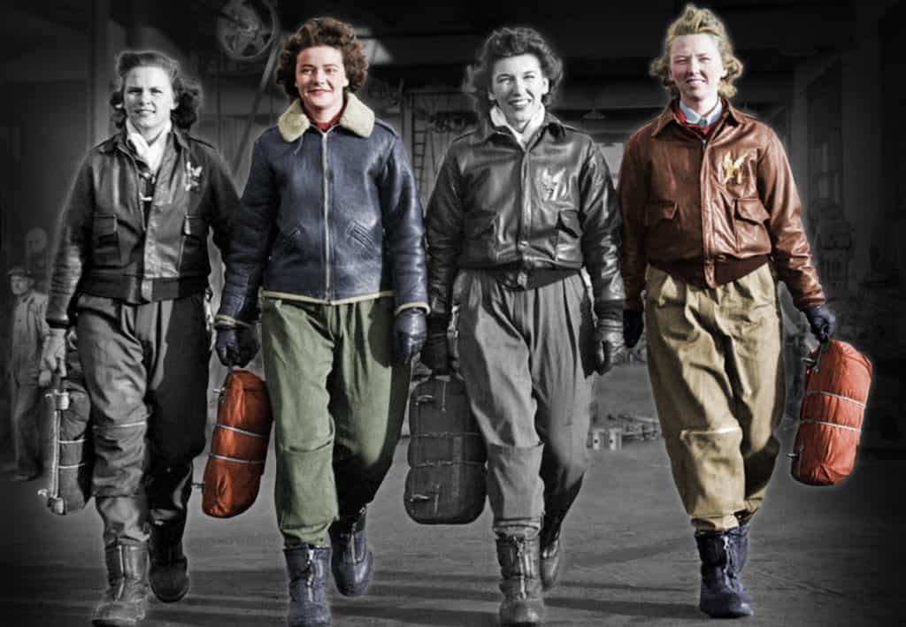 Women in flight suits walking together on a shop floor.