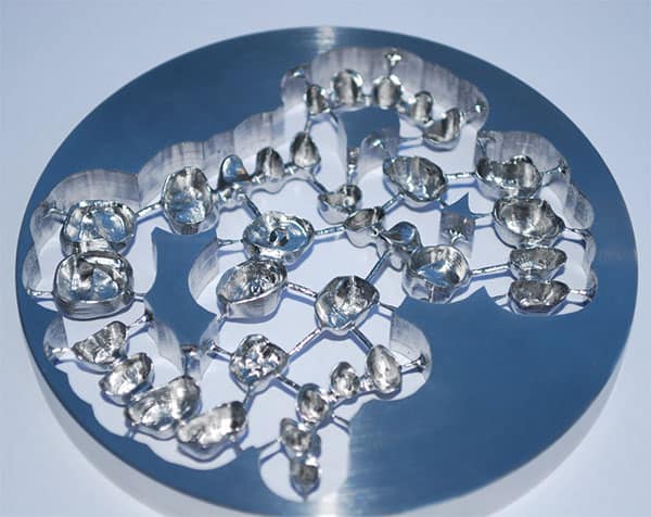 Cobalt chrome dental implants on light blue background, featuring multiple interconnected implants with smooth surface.