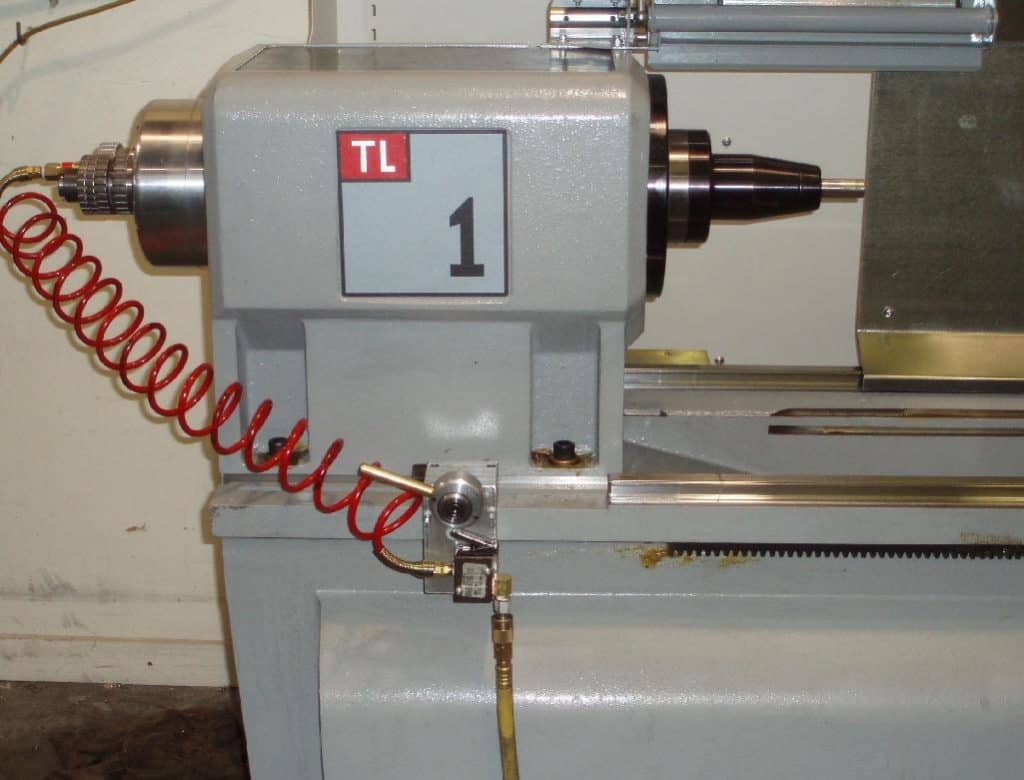 Gray metal lathe with red coiled air hose attached, on a plain white background.