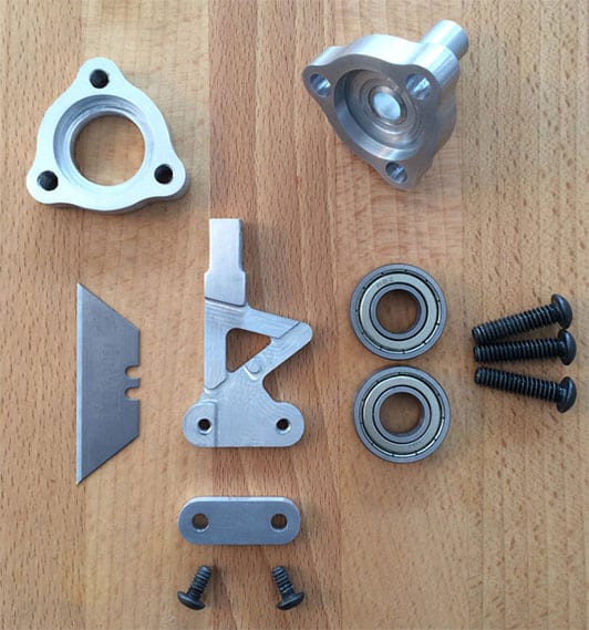 Silver metal parts and screws on a light-colored wooden surface.