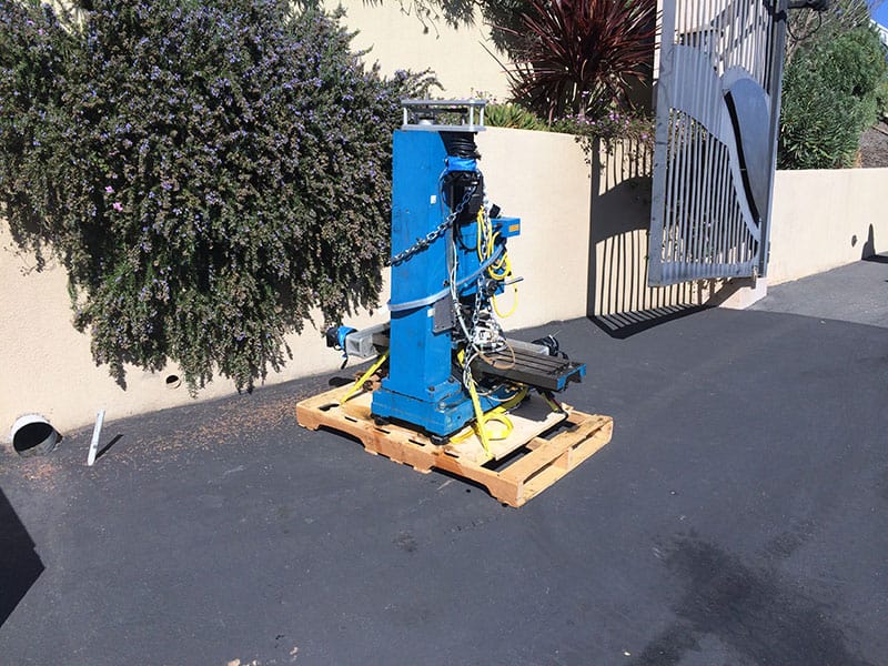 Blue industrial equipment with yellow and black wires on a wooden pallet.