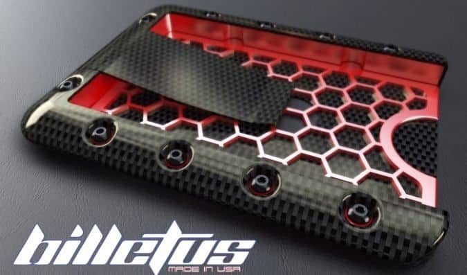 A close-up image of a black and red honeycomb-patterned wallet made from possible carbon fiber material.