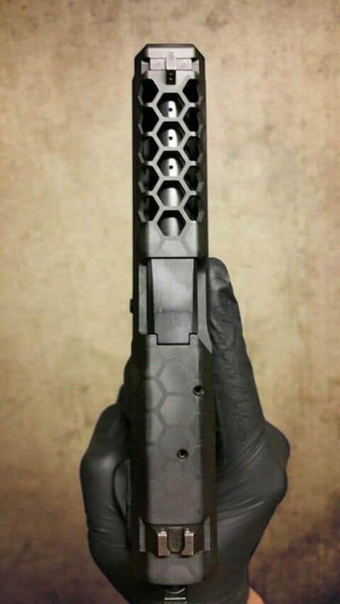 A gloved hand holding a Glock pistol on a dirty concrete floor.