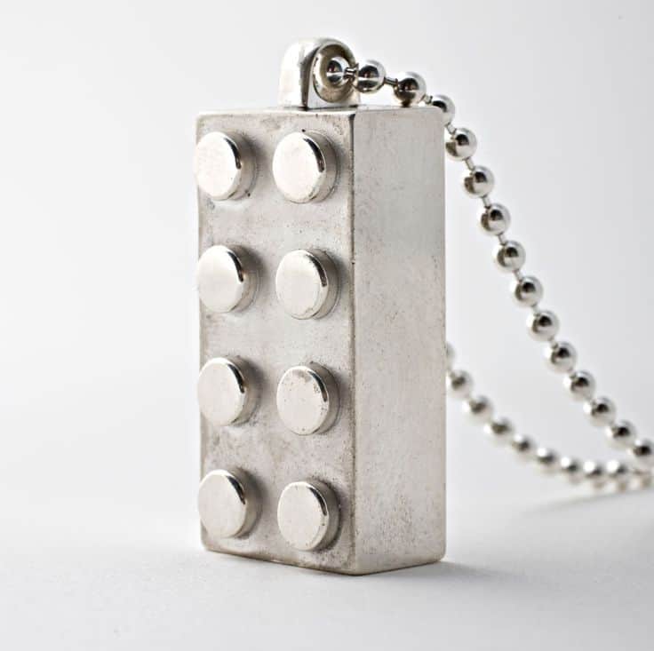 Silver-toned Lego-shaped pendant with raised studs and ball chain.