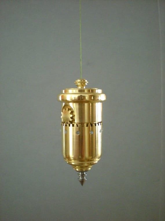 Brass plumb bob with glass weight on gray background.