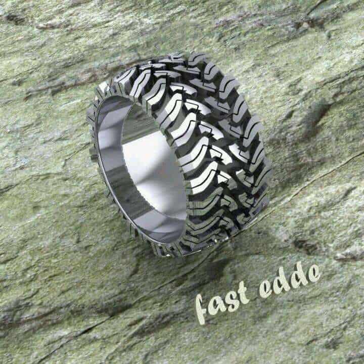 Silver ring with tire tread pattern on a rough stone background.