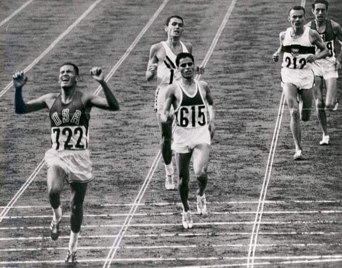 Athletes running towards black finish line.