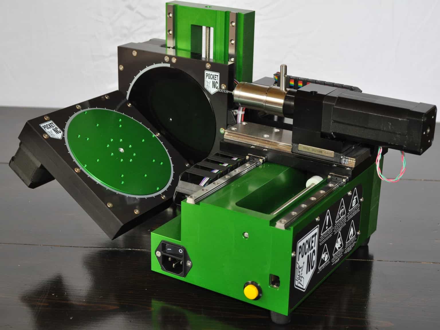 Specialized metalworking device on a dark wooden workbench with circular object and rectangular box.