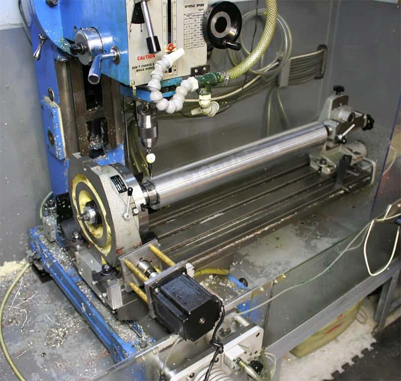 Industrial milling machine with blue frame and metal shavings on its base.