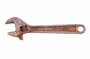 Rusty adjustable wrench with curved jaw and serrated interior.
