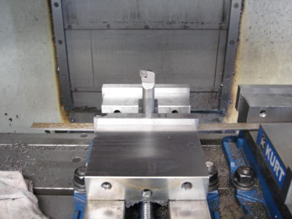 Metalworking vise with central screw and long handle on workbench base.