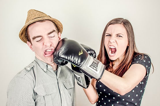 Man wearing fedora being punched by woman in black polka dot dress.