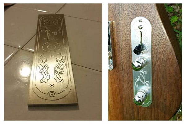 Silver metal panel with engraved leaf design on a white tile floor.