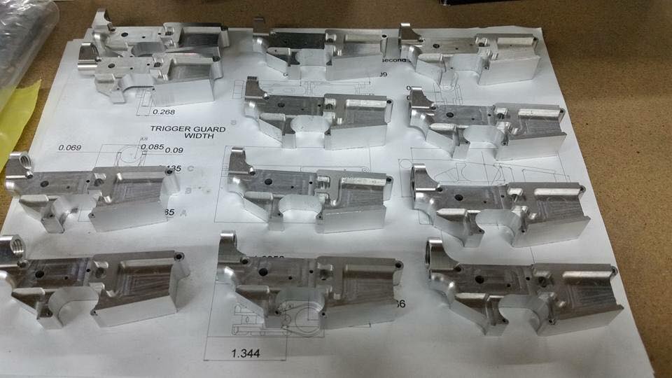 Silver metal AR-15 lower parts on a technical drawing with dimensions and labels.