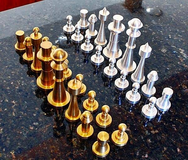 Dark granite surface with gold and silver chess pieces arranged in a chess set.