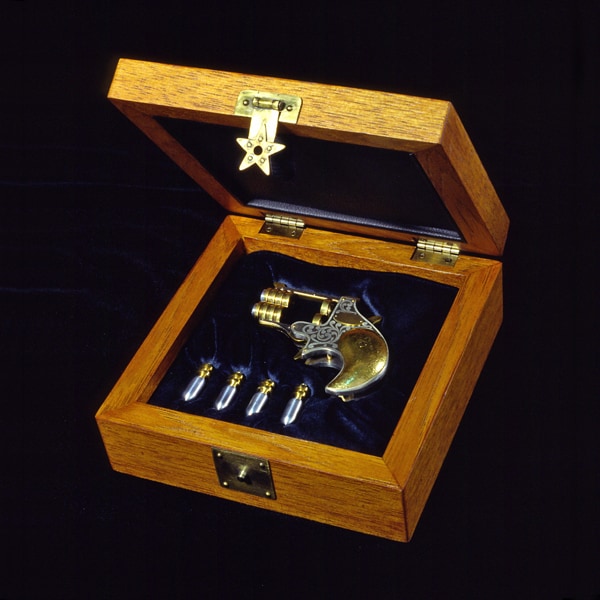 A small wooden box and a derringer pistol on a dark background.