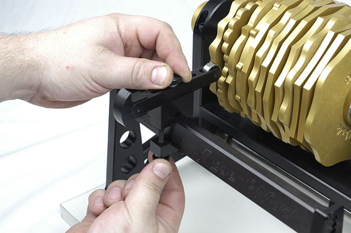 Person adjusting black lever on gold cam with metal frame.