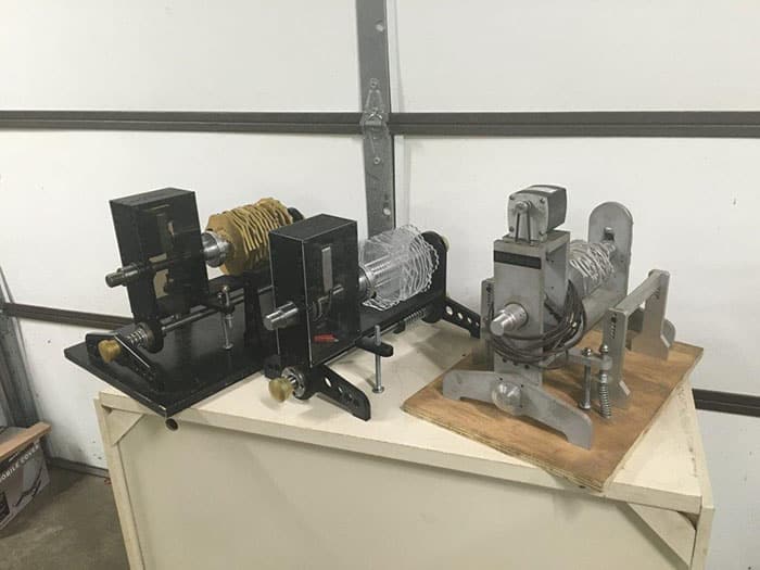 Intricate metal models on a white table against a wall with a door, made from aluminum, steel, and brass.