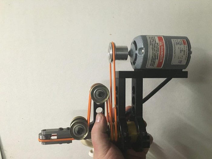 Hand holding complex device with pulleys and motor.