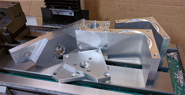Shiny aluminum parts with varied shapes, sizes, holes, and features.