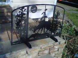 Decorative black metal fireplace grate with tree branch design against a white background.