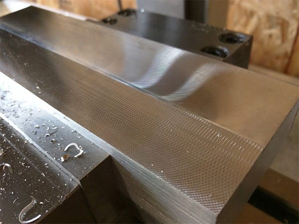 Metal surface with visible tool marks and parallel grooves from machining.