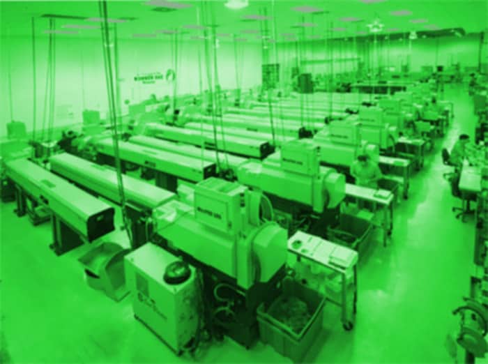 Factory workshop interior with rows of machinery on tables.