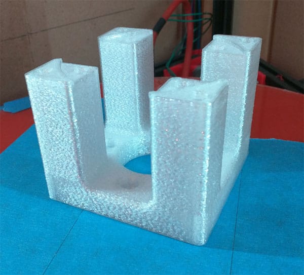 Polystyrene foam U-bracket with circular hole on background with cardboard box and tools.