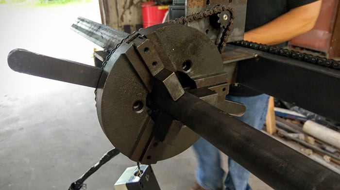 Heavy-duty lathe chuck with four-jaw self-centering design and adjustable tailstock.