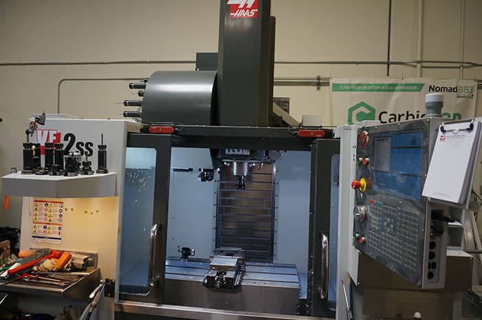 Large metalworking machine with black column and metal table.