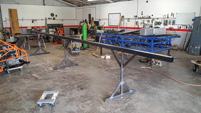 Well-lit workshop with various machinery and equipment, featuring a large metal frame on a stand.