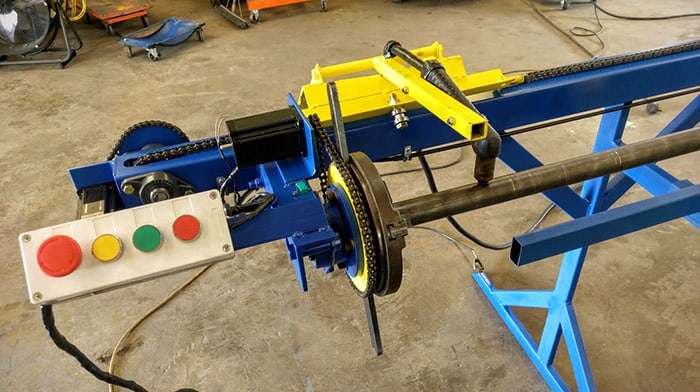Blue and yellow machine with control panel and tools in a workshop setting.