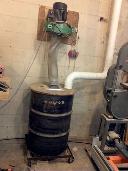 A dust collection system featuring a large cylindrical container with attached hose.