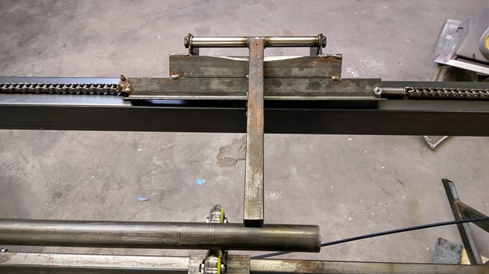 Metal framework with multiple chains on a concrete floor.