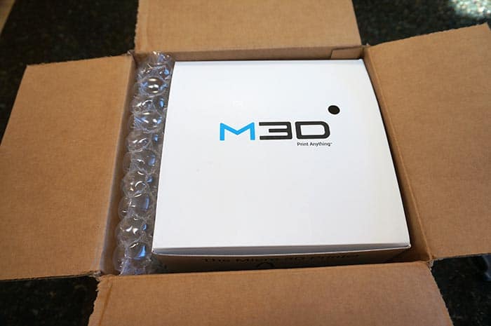M30 3D printer wrapped in bubble wrap on a cardboard box.