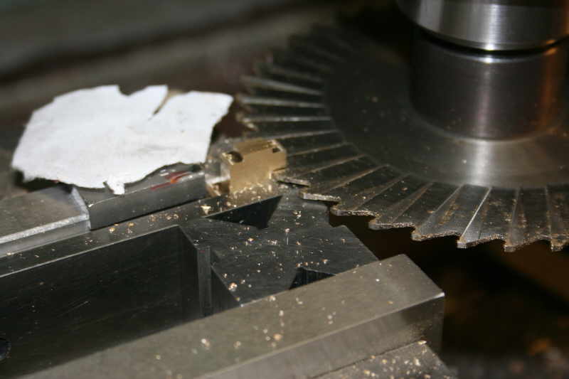 Metal gear with torn paper on top in a workshop setting.